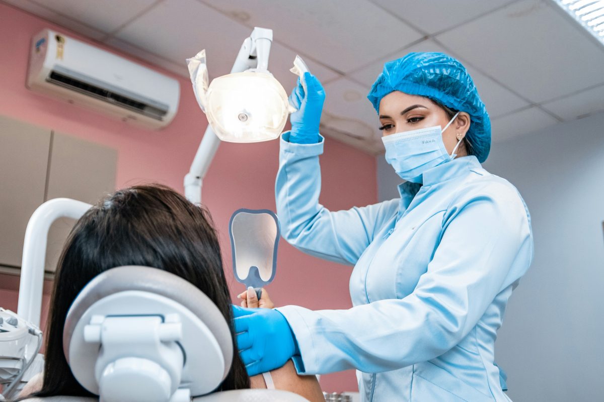 Dentist wearing a mask and gloves examining a patient's teeth in a dental clinic