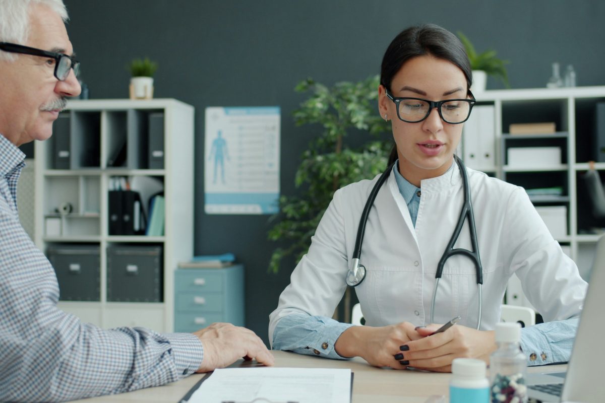 Doctor in a white coat consulting with an older male patient in a clinic office