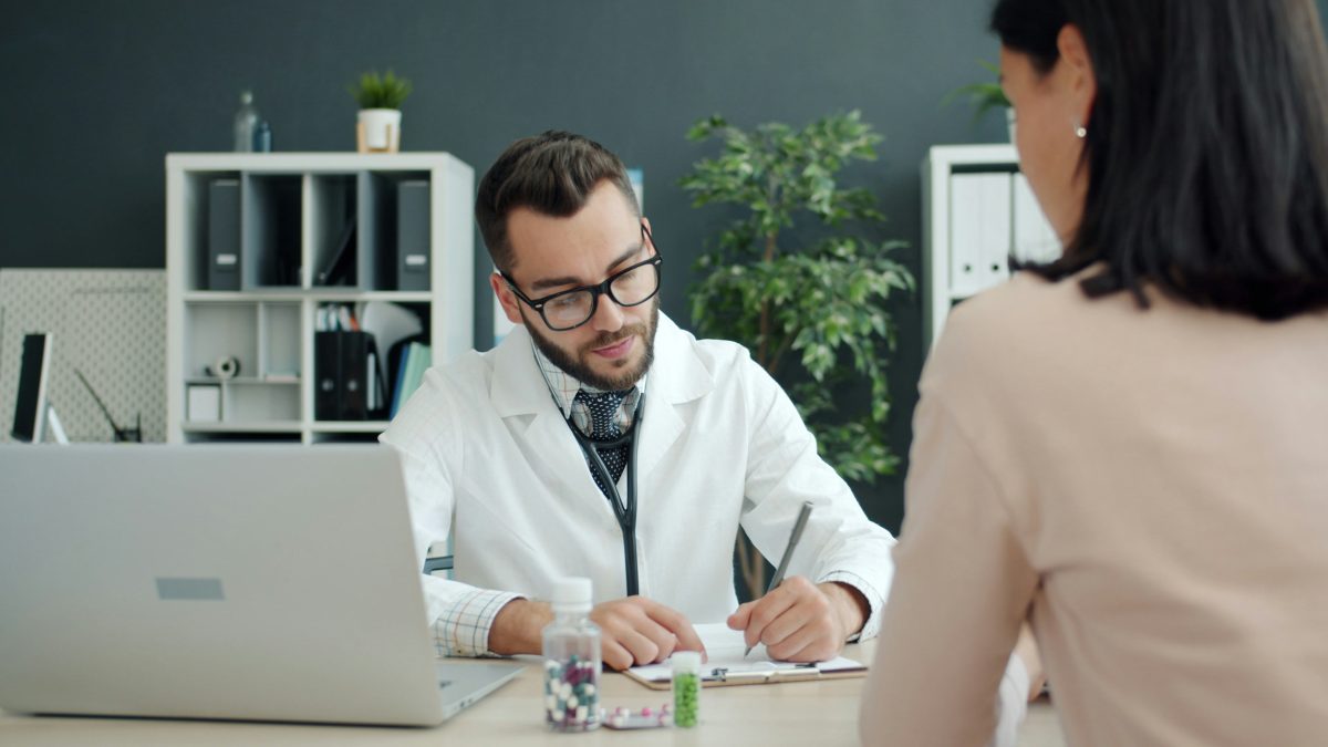 Doctor writing notes while consulting a patient during an OPD visit at a private hospital