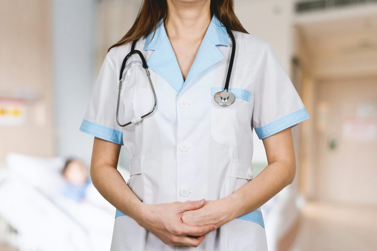 Lady doctor in a white uniform with a stethoscope standing in a hospital ward